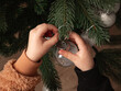 Kind hängt Weihnachtskugeln an einen Weihnachtsbaum