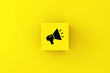 Announcement, communication, speech and voice concepts. Megaphone symbol on a yellow cube block.