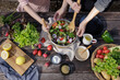 Mother and daughter preparing fresh vegetable salad with fresh vegetables, tomatoes, bell pepper, potato, fruits and dipping sauces on wooden desk at outdoor garden, Conceptual of party family healthy
