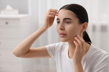 Wall Mural - Woman with dry skin checking her face indoors