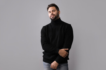 Wall Mural - Handsome man in stylish black sweater on grey background