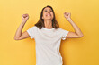 © Asier - Middle-aged caucasian woman on yellow celebrating a victory, passion and enthusiasm, happy expression.