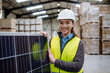 © Halfpoint - Female worker carrying solar panel in warehouse, factory. Solar panel manufacturer, solar manufacturing.