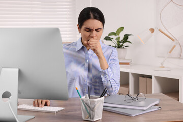 Sticker - Woman coughing while using computer at table in office. Cold symptoms