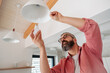 Man changing LED bulbs at home. Concept of energy efficiency, longevitiy and environmental impact of electronic bulb.