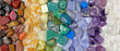 Chakra Crystal Healing wide Background template - Rows of tumbled polished healing crystal laid out in chakra colours white, purple, blue, green, yellow, orange, red ideal for crystal healing theme
