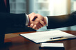 Two businessmen shake hands while signing a contract lying on the table. Conclusion of a contract between two entities by a bank or an insurance company.