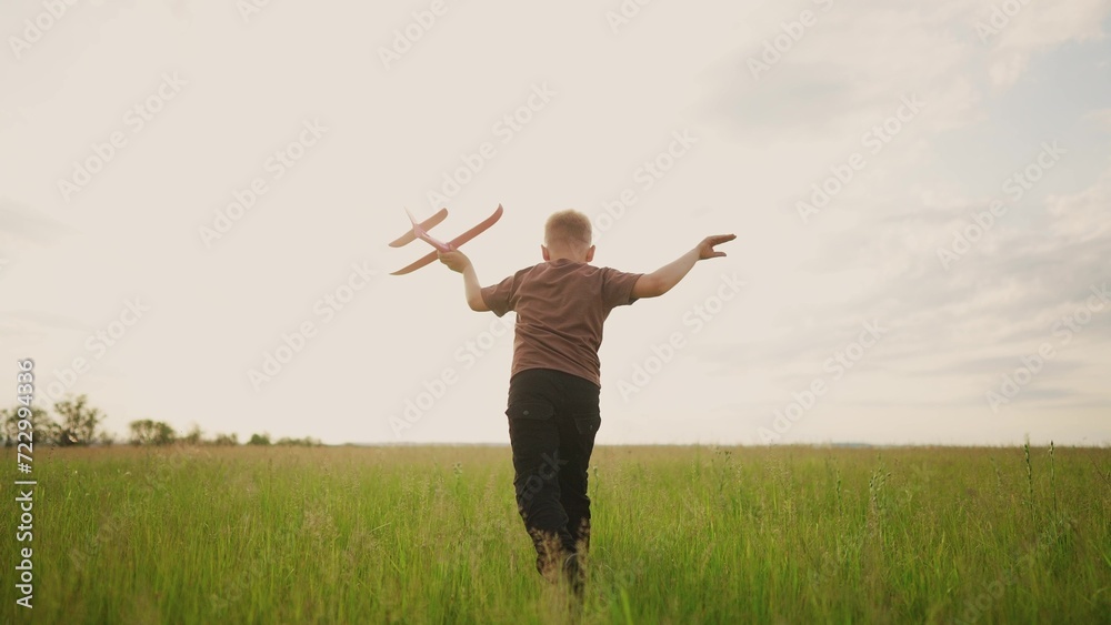 a little boy running in the park on the grass with a toy airplane in ...