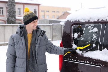 Canvas Print - Man cleaning snow from car window outdoors