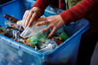 © ADDICTIVE STOCK CORE - High angle of hands of an anonymous person sorting through a variety of recyclable materials in a blue bin, demonstrating the everyday practice of separating recyclables
