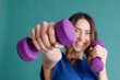 © VISTA by Westend61 - Happy woman with purple dumbbells against blue background