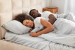 © Prostock-studio - Young affectionate african american spouses sleeping in bed embracing indoor