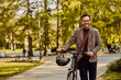 © Jelena - Portrait of happy businessman pushing his bicycle through a park while going home from a workday.