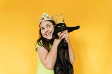 Happy Girl And Cat Wearing Crown Against Yellow Background