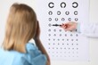 © New Africa - Ophthalmologist testing little girl's vision in clinic, back view