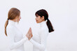 © VISTA by Westend61 - Young women touching hands while looking at each other against white background