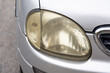 Hazy opaque yellowed front head lamp of car reduces light pass-through and driving visibility
