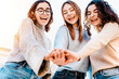 Happy smiling group of young women people stacking hands outdoors - Girl friends celebrating success on city street - Youth community concept with female standing together supporting peace and love