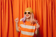 © VISTA by Westend61 - Happy woman with clenched fists dancing in front of orange curtain