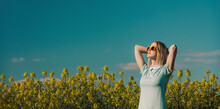 Woman With Hands Behind Head Standing In Field At Sunny Day