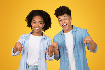 Wall Mural - Happy African American young woman and man pointing directly at the camera with cheerful expressions