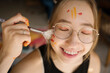 © VISTA by Westend61 - Happy woman painting face with paintbrush