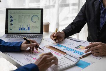 Two business partners colleagues discuss financial and company planning graphs during budget meeting in office, close-up view