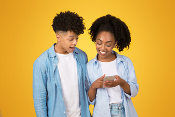 Wall Mural - A young African American woman smiling while showing something on her smartphone