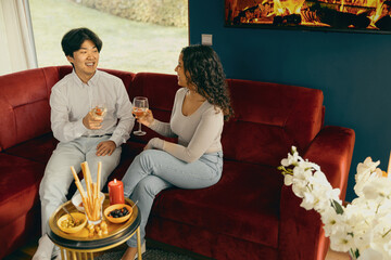 Wall Mural - Smiling friends enjoying in conversation and drinking wine during holiday party at home