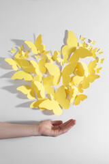 Wall Mural - Woman with yellow paper butterflies on white background, top view