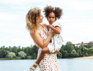 A young mother plays with her daughter on the beach near the lake.