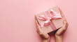 a gift box wrapped in pink ribbon lies open in a woma