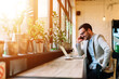 © bnenin - Side view of a smiling businessman talking on a phone while sitting at the restaurant.