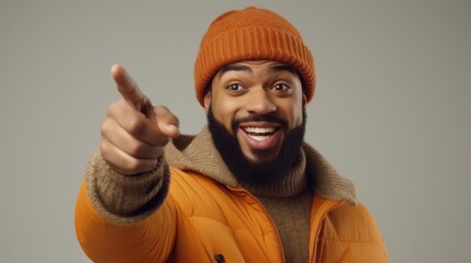 Poster - A man wearing an orange jacket is pointing directly at the camera. This image can be used to convey a sense of confidence, engagement, or to emphasize a specific message