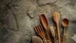 An assortment of wooden cooking tools laid out against a rugged stone surface, emphasizing a natural and minimalist culinary theme