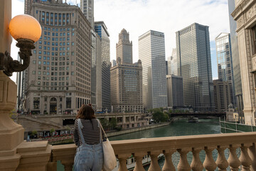 A girl watches the river passing through the buildings of the city