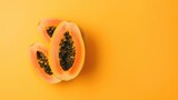 A single papaya fruit, pastel orange background