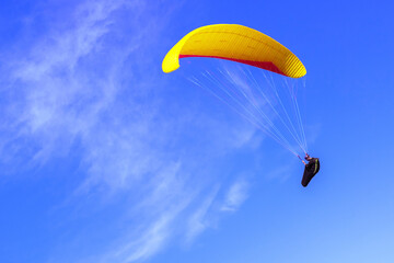 Freedom concept: paraglider flying on the background of blue sky with clouds