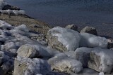 Fototapeta Miasto - Ice formed on rocks at edge of lake