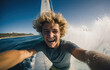 Handsome male windsurfer takes extreme selfies on a windsurf board with a sail, indescribable strong emotions