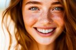 Close-up portrait of a joyful young woman with freckles smiling brightly, showcasing natural beauty and happiness.