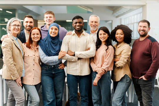 Group portrait of smiling multiracial business people looking at camera. Confident workers, colleagues  standing in modern office. Meeting. Successful business, career, startup team 