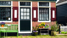 A Street In Amsterdam In Early Spring. A Cozy Cafe In Dutch Style. Exterior Of A Rustic Cafe. House Easter Decoration With Spring Bulb Flowers. Green Wooden Bench In The Exterior.