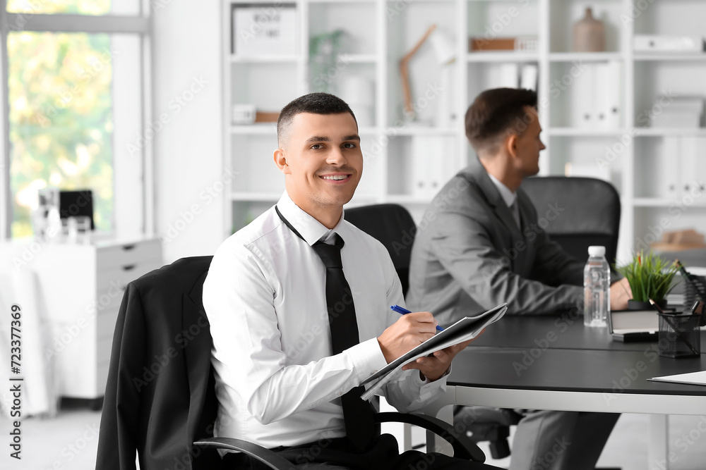 Businessman with notebook negotiating at table in conference hall