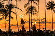 Palm trees at  beach in tropical location against brilliant orange sunset sky with burning torches in foreground.