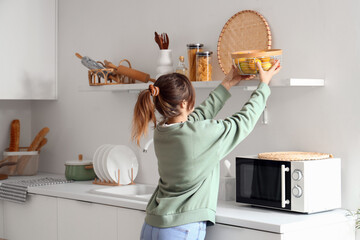 Poster - Pretty young woman with fruit basket in modern kitchen interior