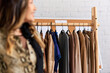 © LIGHTFIELD STUDIOS - blurred asian clothes stylist smiling near rack with fashionable clothes in atelier, small business