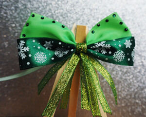 On a gray background on a wooden stand there is a green satin bow with snowflakes with stones for dogs. pet accessories for christmas