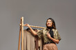 © LIGHTFIELD STUDIOS - young happy asian clothes stylist posing near rack with trendy bespoke clothes on grey backdrop