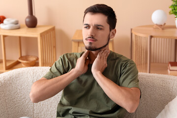 Canvas Print - Young man with thyroid gland problem at home